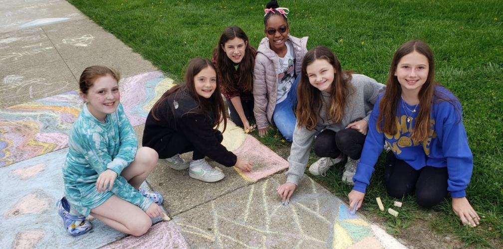 students smiling while drawing with chalk